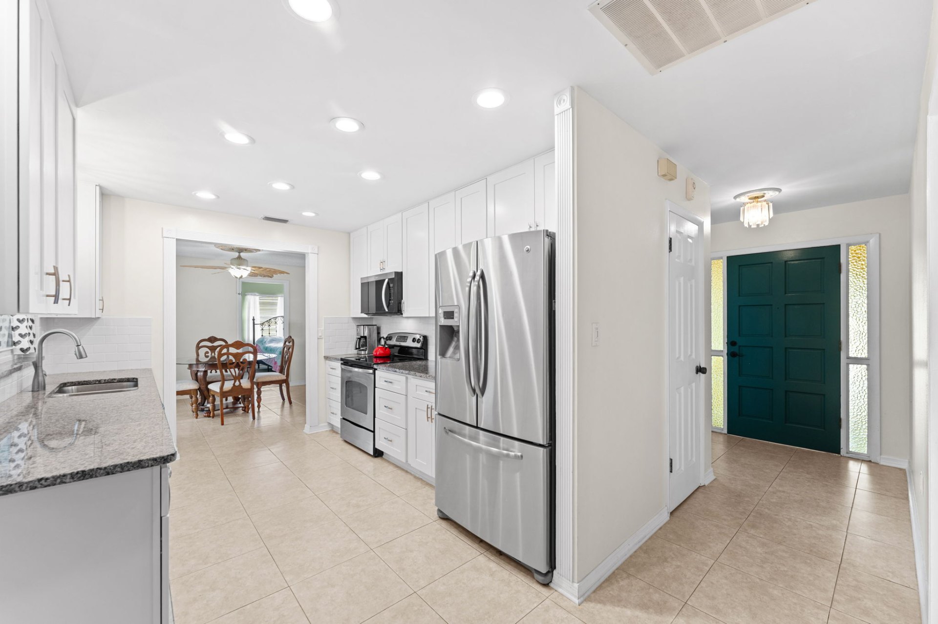 Kitchen and foyer with stainless French-door refrigerator and teal front door