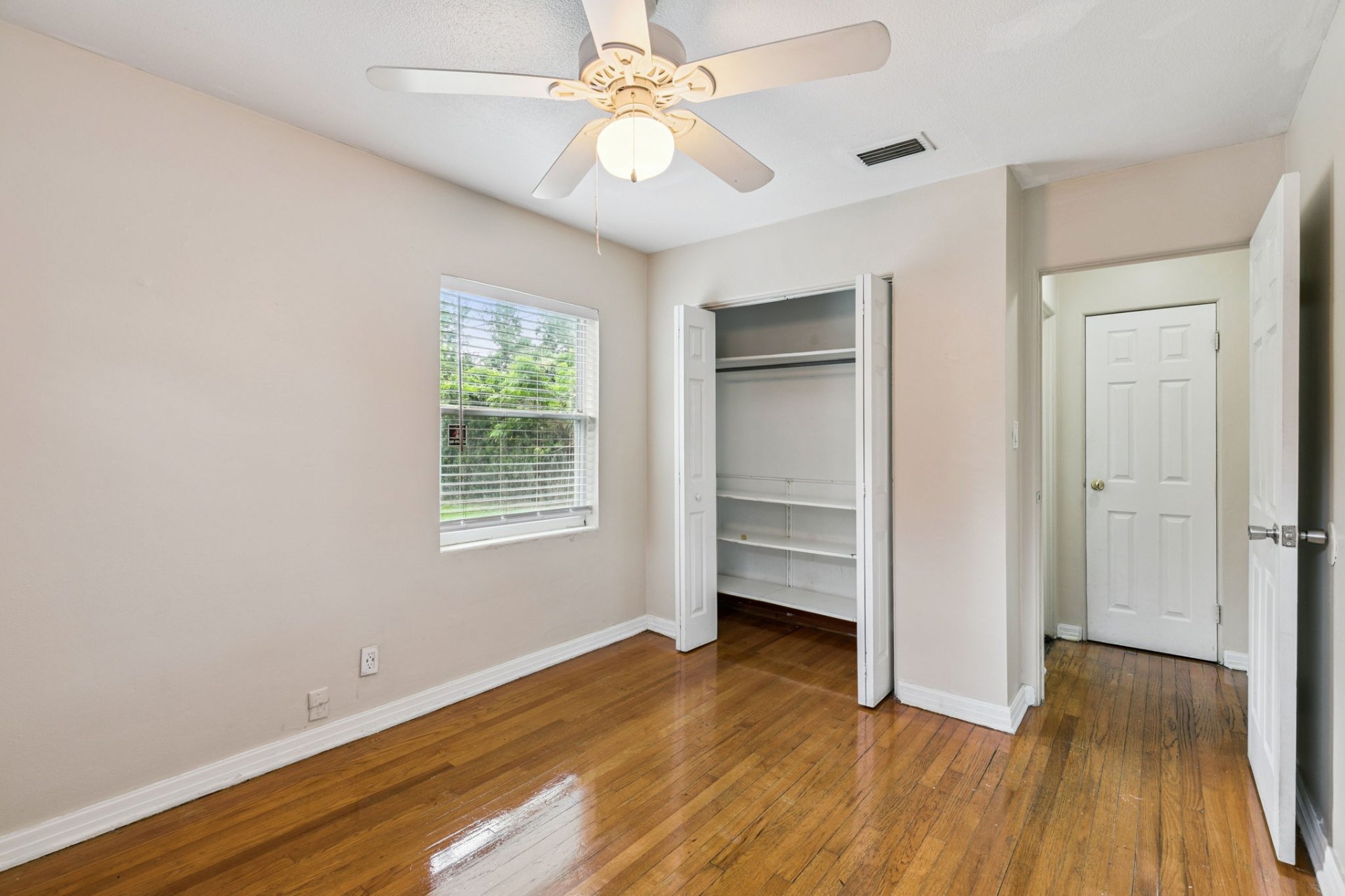 Bedroom featuring a wide closet with built-in shelving and warm refinished hardwoods