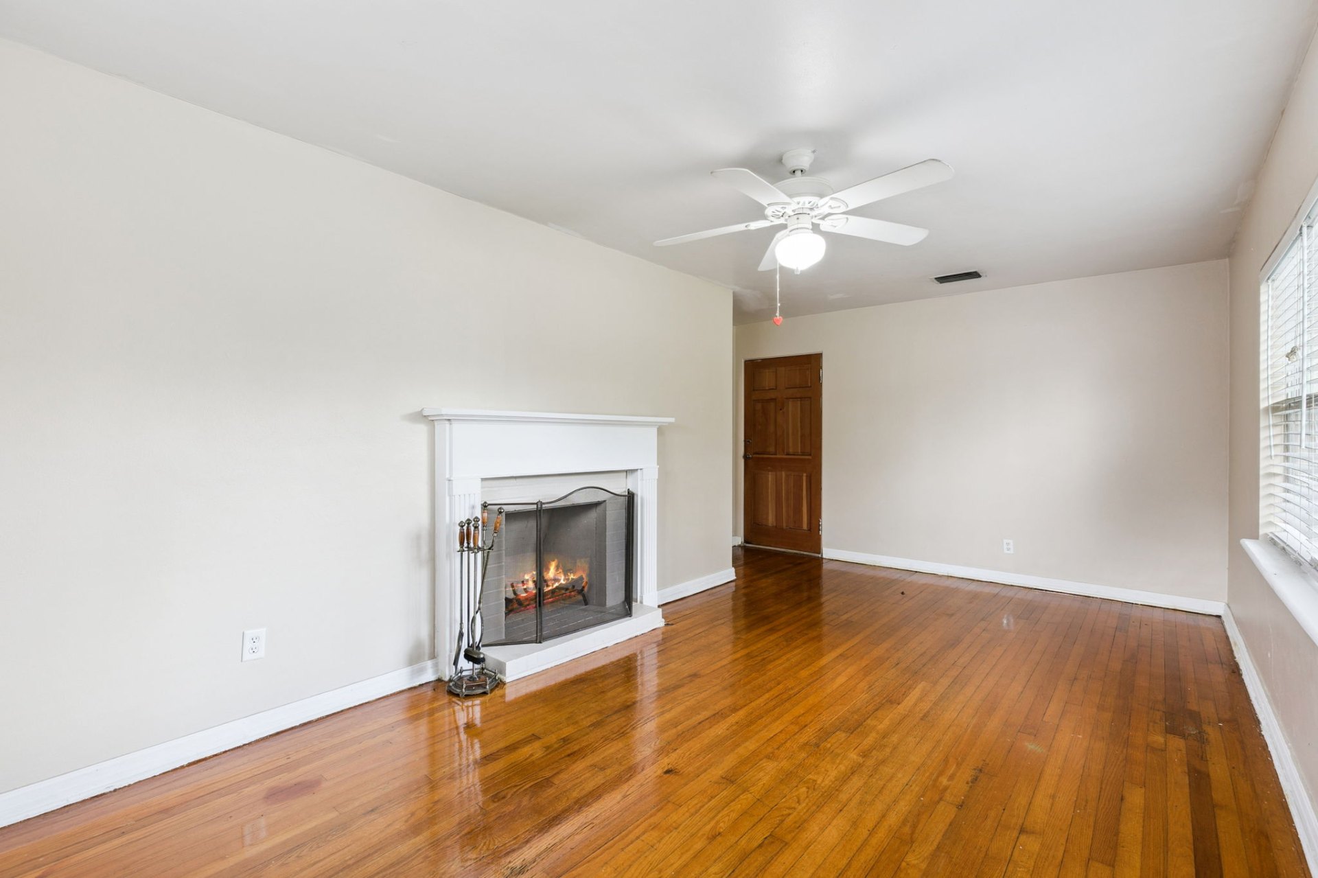 Wood-burning fireplace with classic white mantel anchoring the hardwood-floored living room