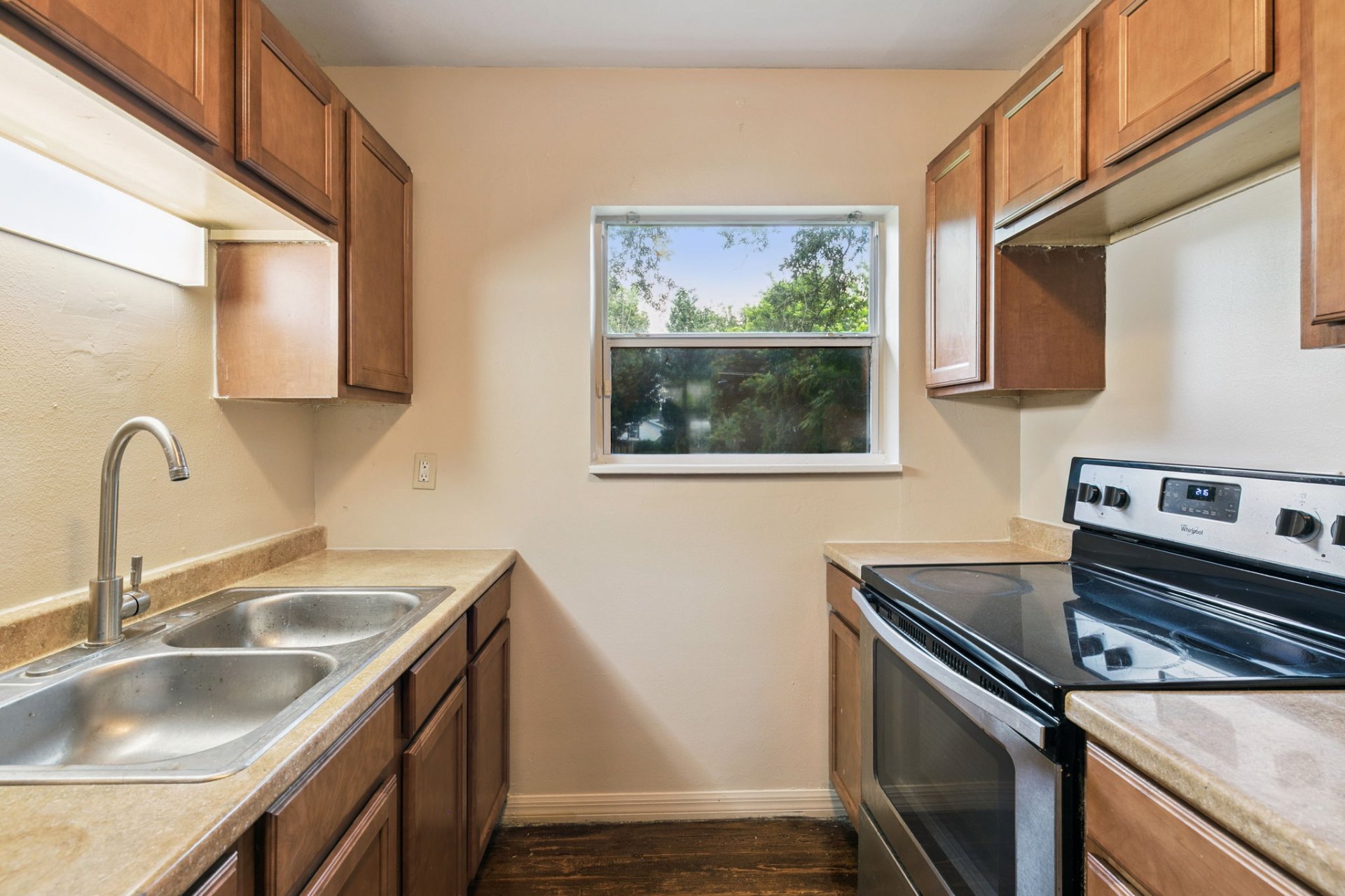 Kitchen with stainless glass-top range, double sink, and abundant cabinet storage under a bright window
