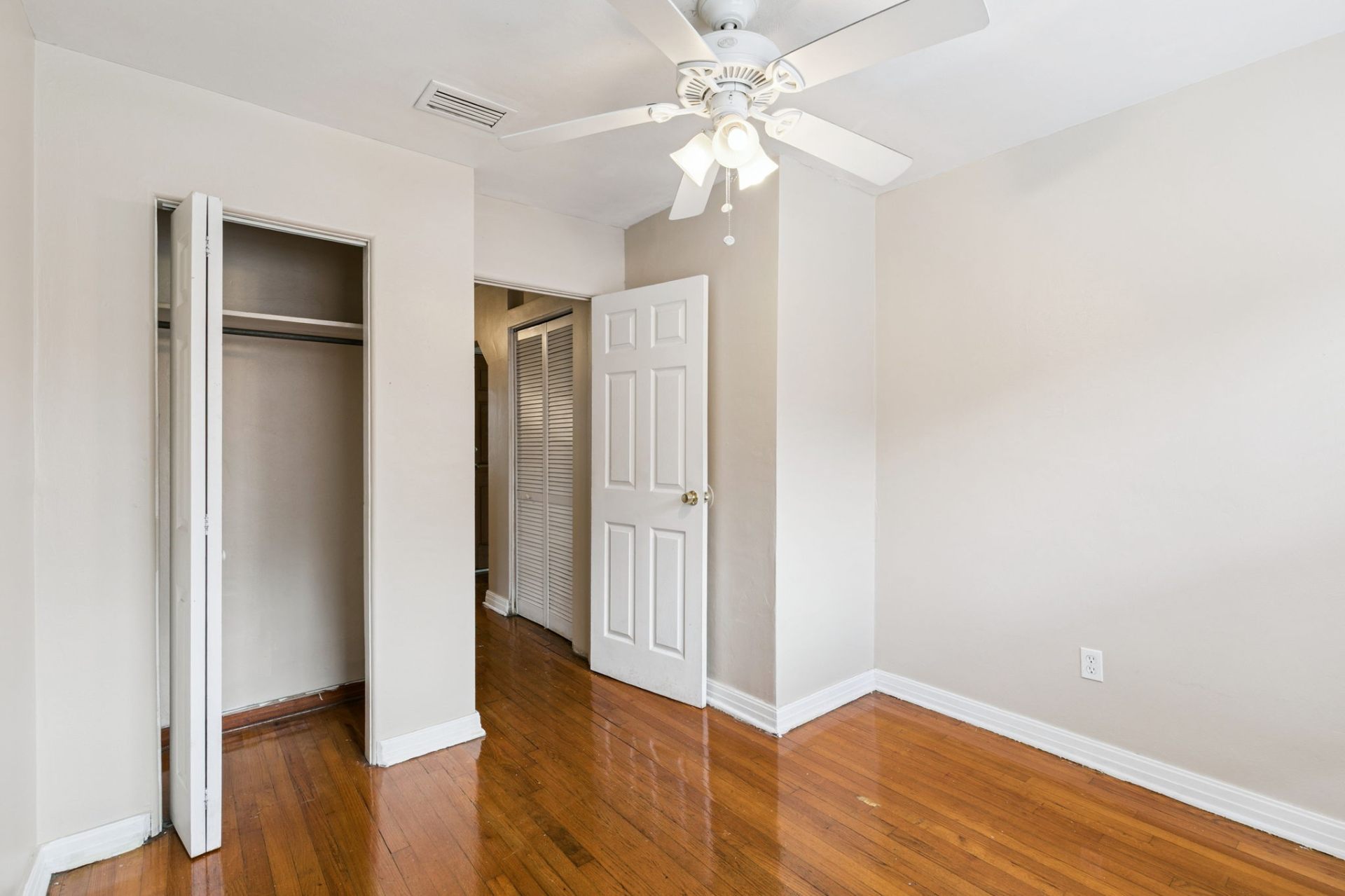 Bedroom with refinished hardwood floors, ceiling fan, and roomy closet off the central hallway
