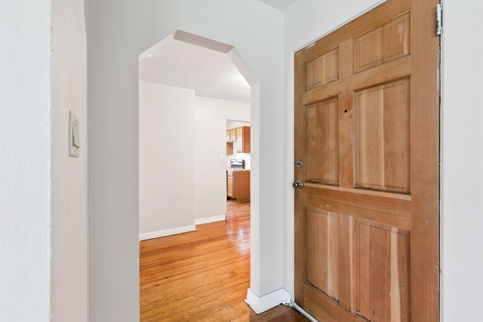 Welcoming entry with original wood door and vintage archway opening to the main living space