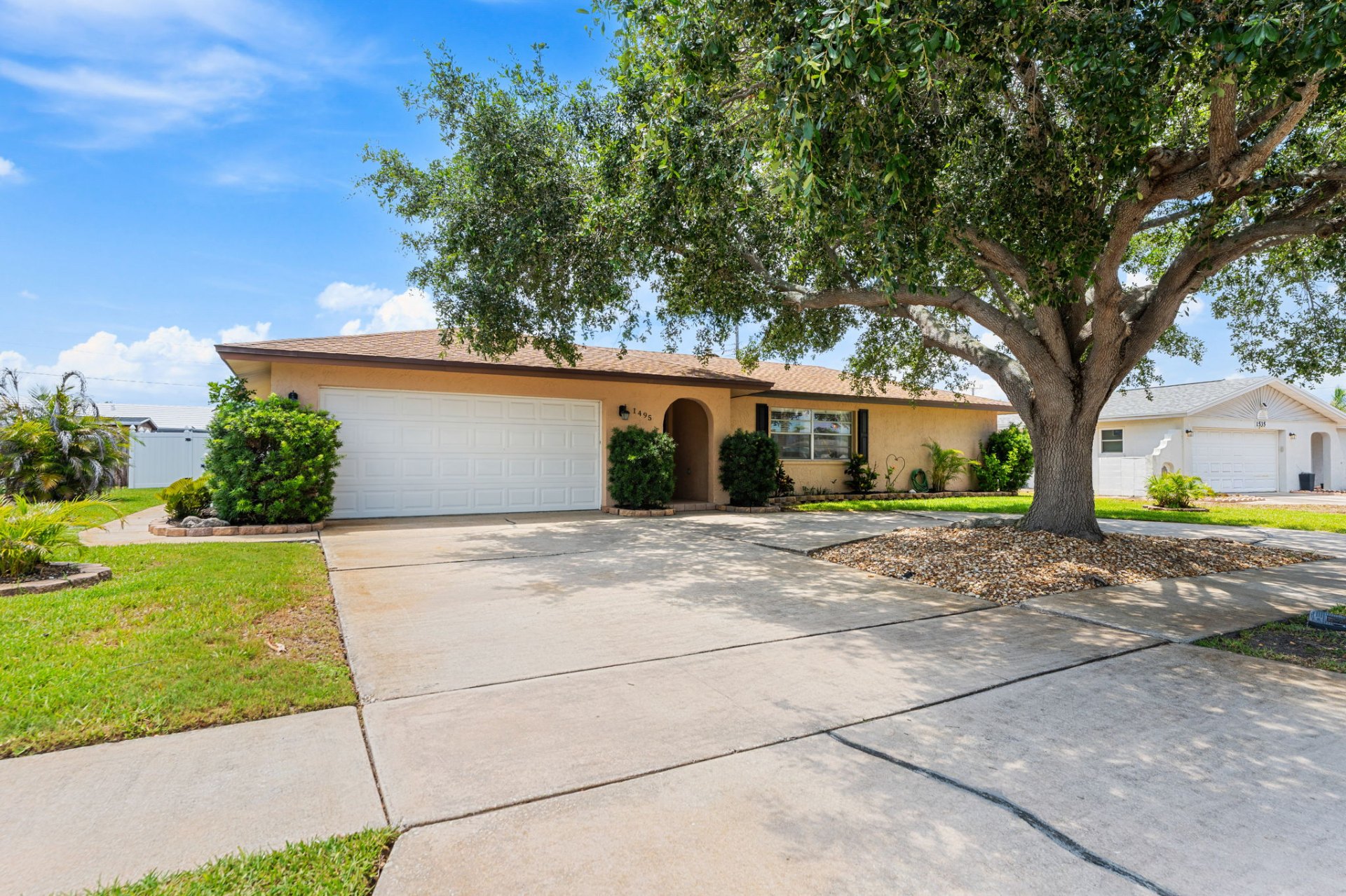 Front exterior with mature oak tree and 2-car garage