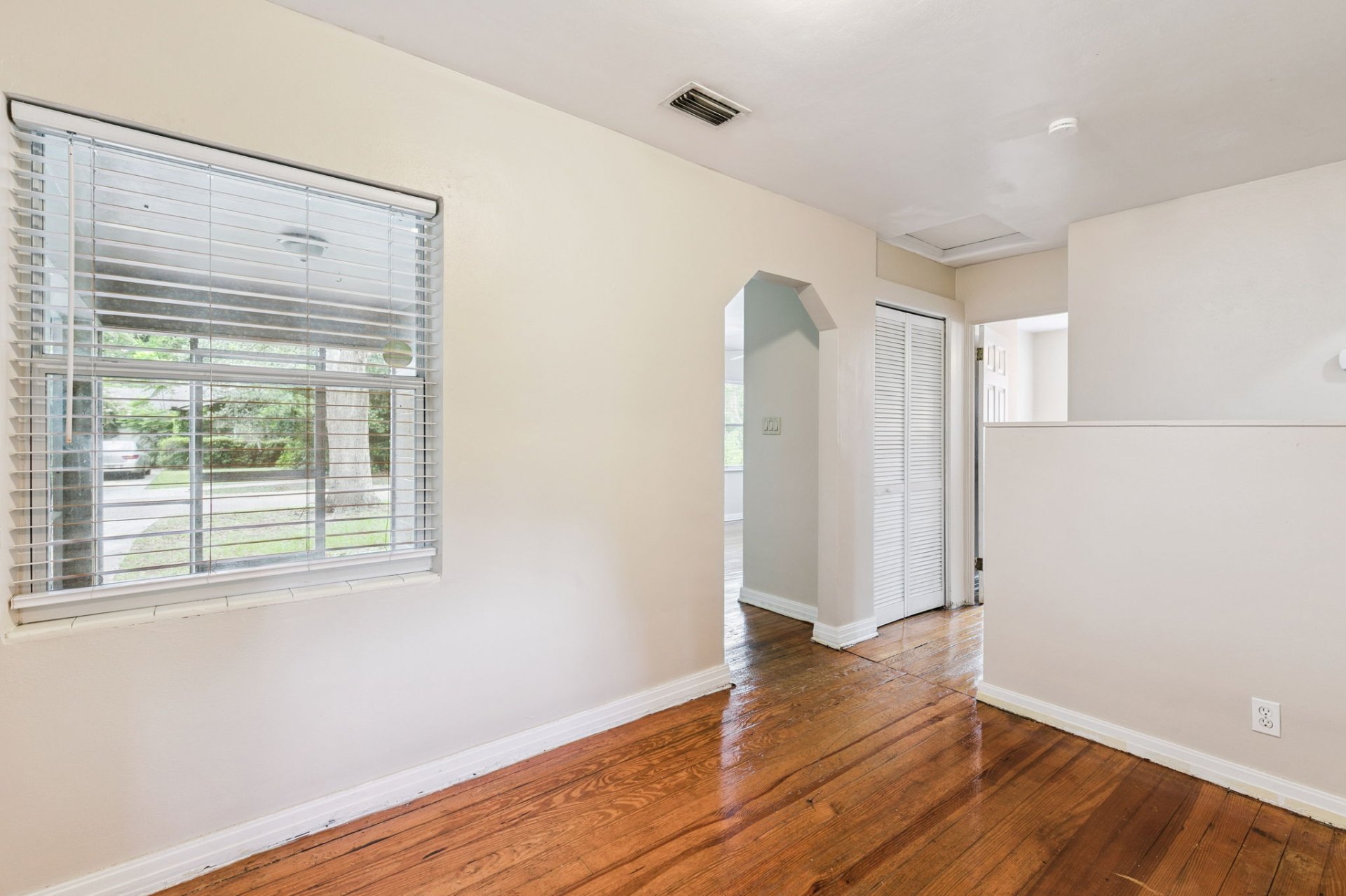 Versatile dining room with large front-yard window, closet storage, and original hardwood floors