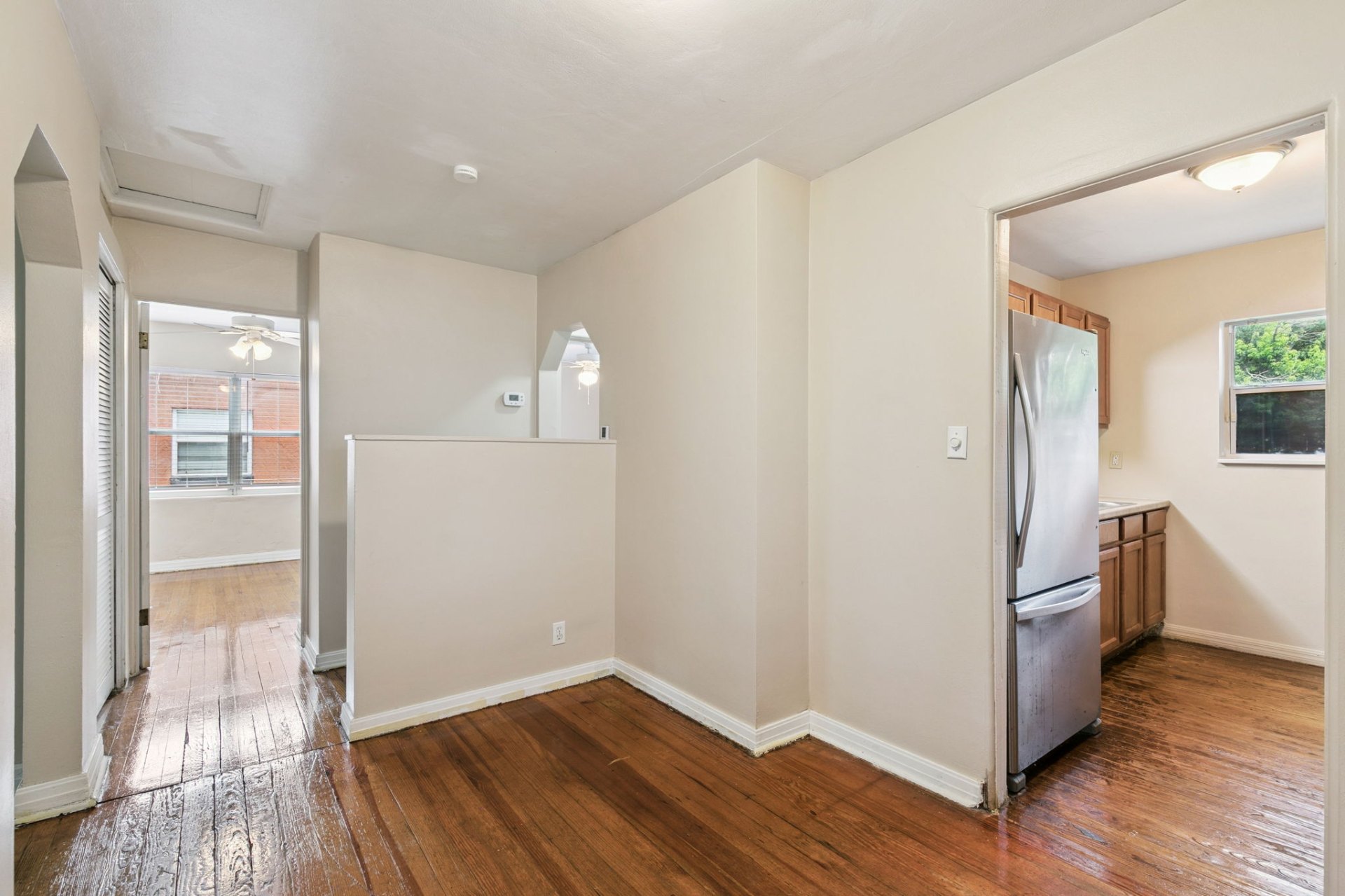 Open dining nook with gleaming hardwoods flowing to the kitchen and bedroom wing
