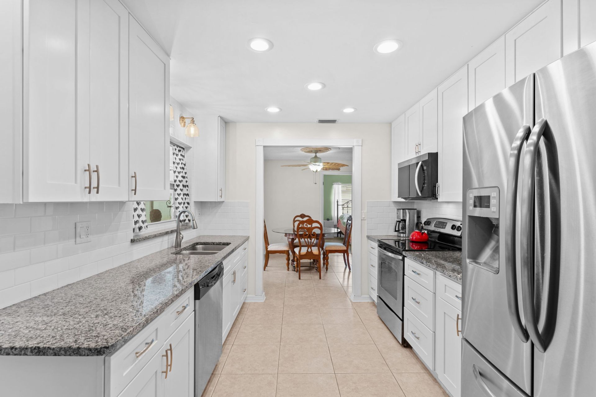 Galley kitchen with white shaker cabinets, granite counters and stainless appliances