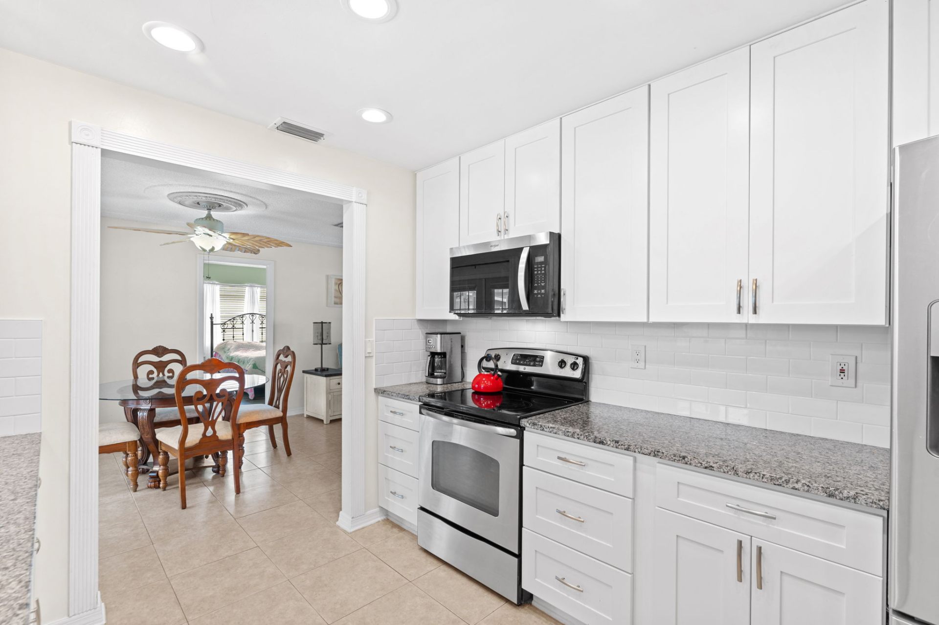 Kitchen with white shaker cabinets, granite counters and stainless range