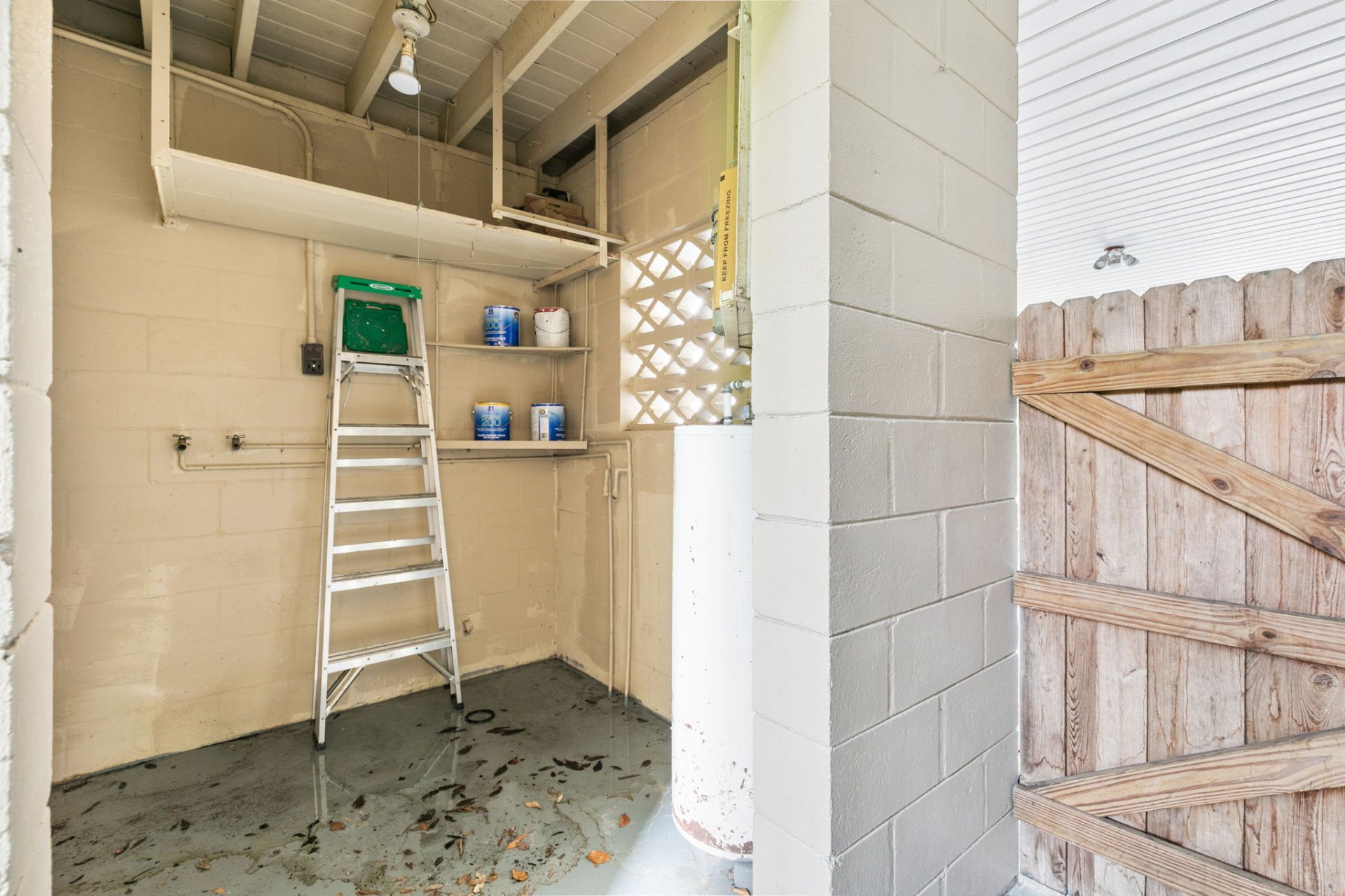 Enclosed workshop and storage room off the carport with built-in shelving and utility hookups