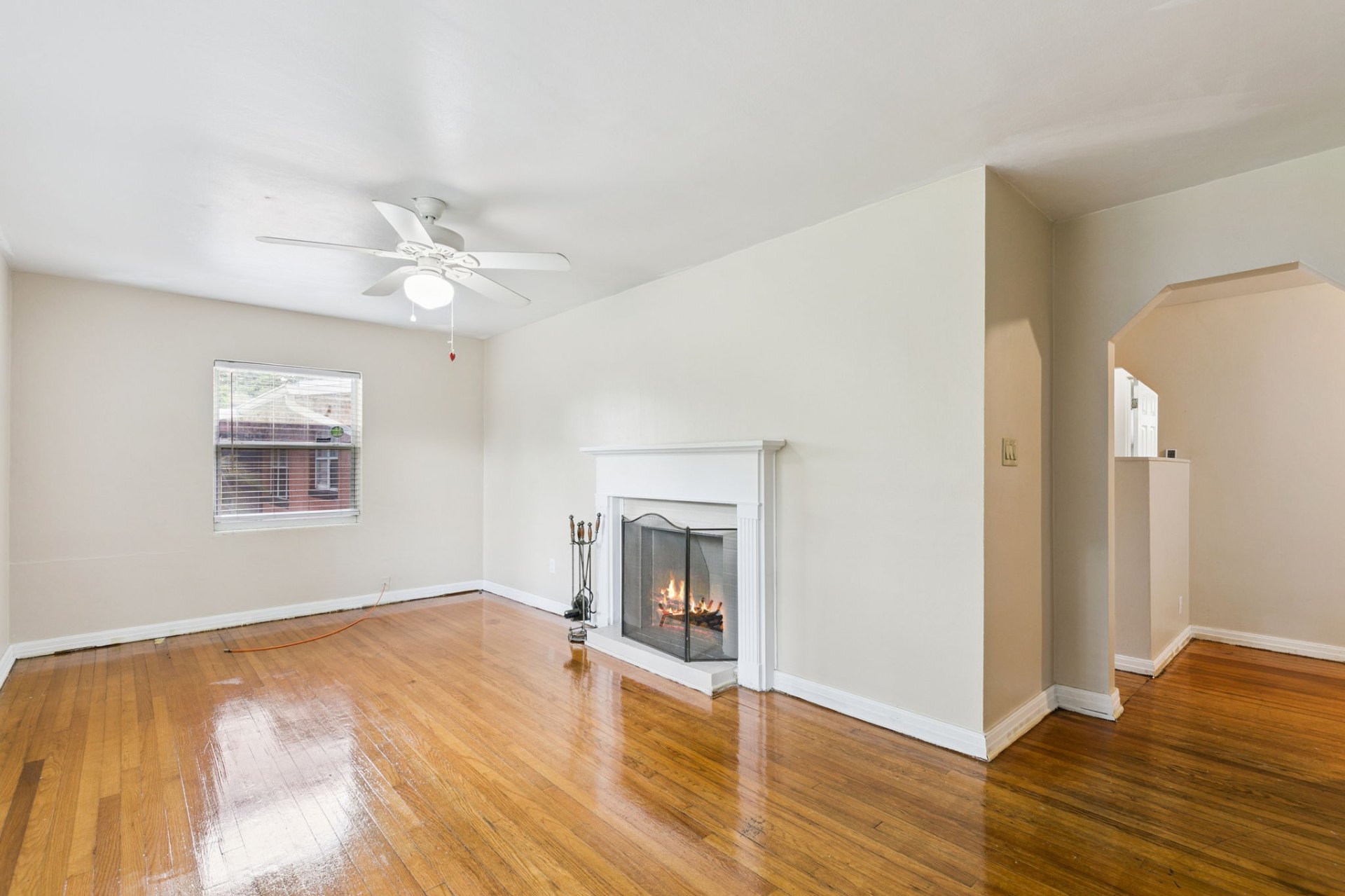 Living room with glowing fireplace and original arched doorway leading to the dining area