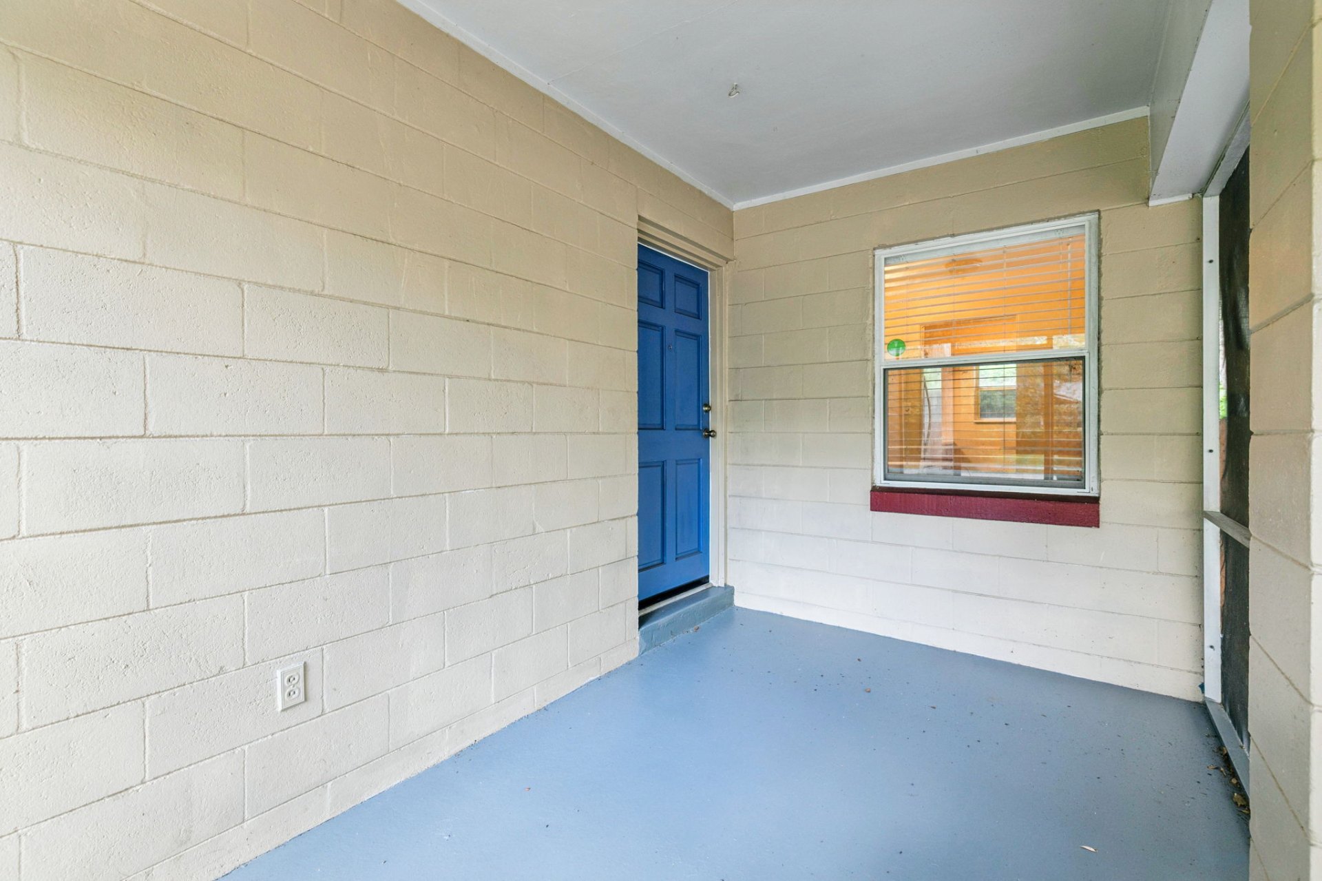 Screened front porch with freshly painted blue floor and classic cobalt-blue front door
