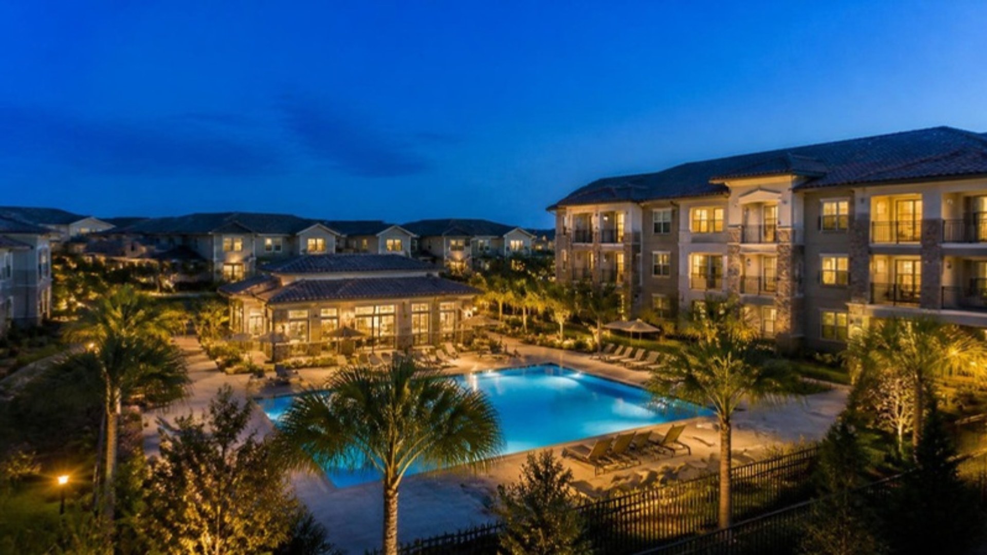 Orlando garden-style apartment community with a lit pool at twilight