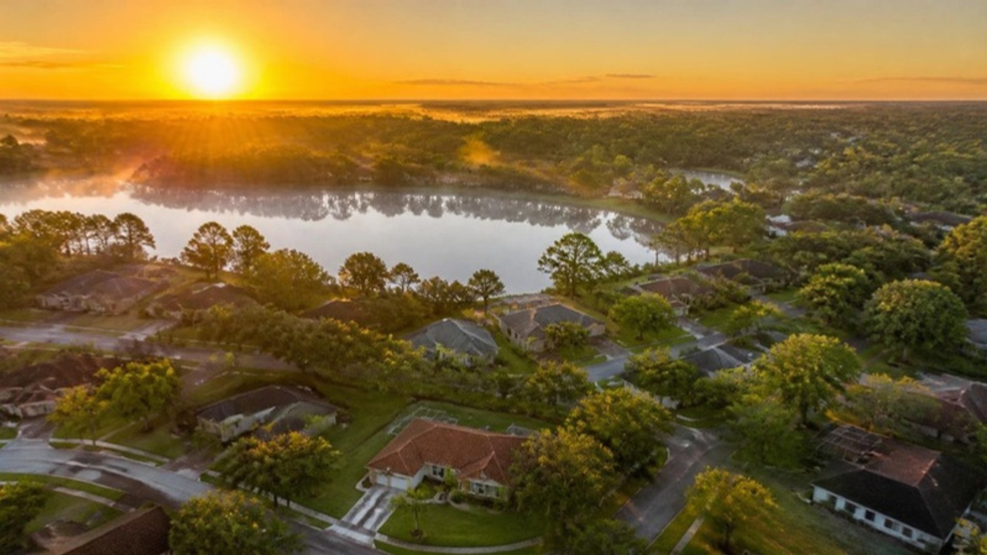 Aerial sunrise view of a Central Florida neighborhood around a small lake