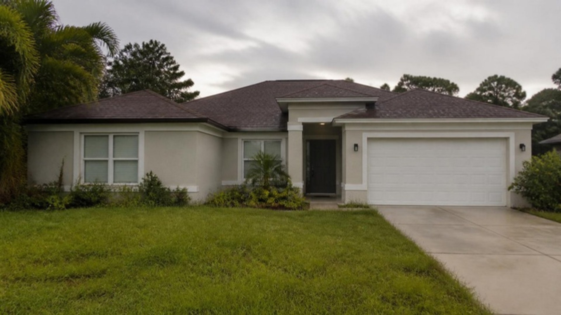 Quiet Florida home under an overcast sky with closed blinds and an empty driveway